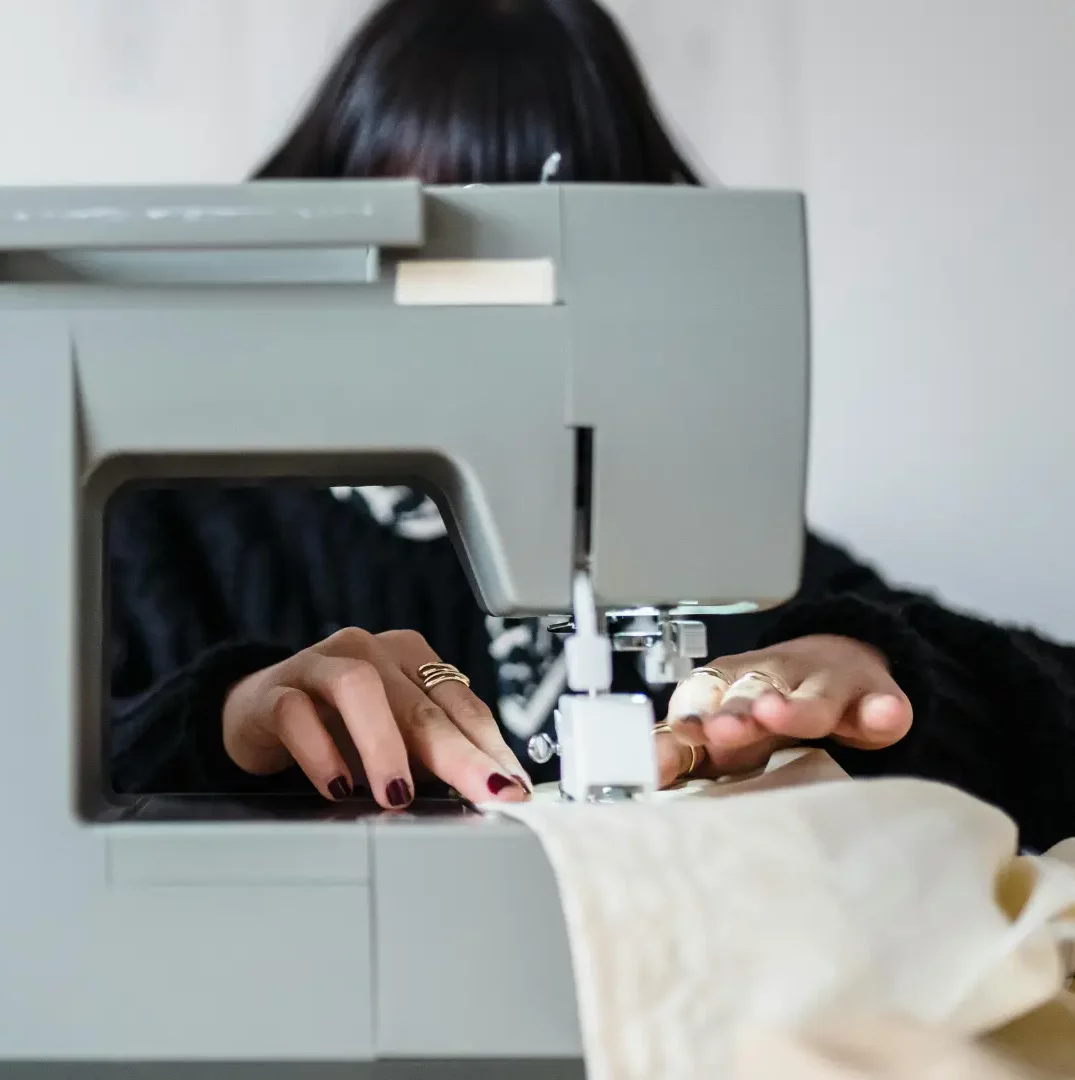 Femme en train de coudre dans l'atelier des Simones, symbolisant l'accueil et le soutien.